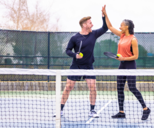 Two people high fiving on a pickleball court