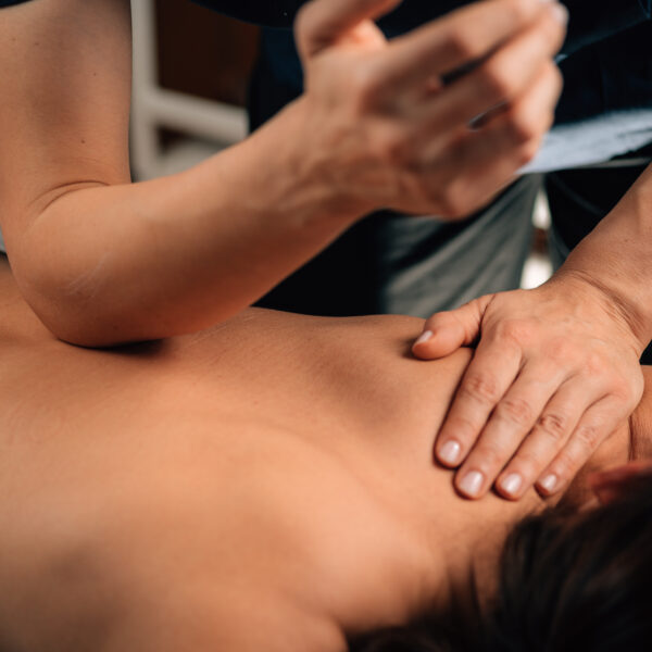 Massage therapist using elbow and hand pressure during a deep tissue massage on a client’s back.
