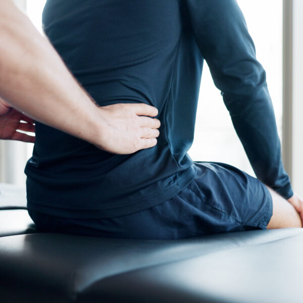 Therapist applying pressure to a client’s lower back during a massage session to relieve pain and tension