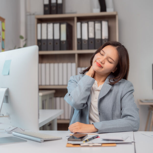 Female therapist giving chair massage in office to help employee relax