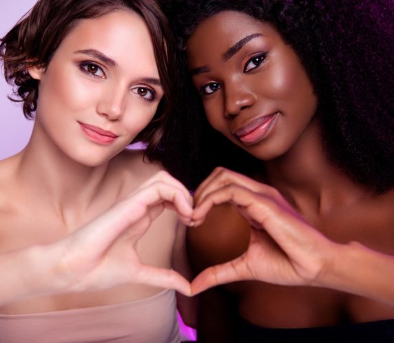 Portrait of two pretty charming girlfriends hands fingers make heart symbol perfection isolated on neon light background